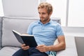 Young man reading book sitting on sofa at home Royalty Free Stock Photo