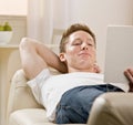 Young man reading book on sofa at home Royalty Free Stock Photo