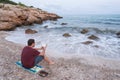 Young man reading on a Mediterranean beach