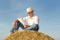 Young man reading on top of a straw bale