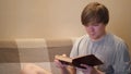 Young man reads book with interest. Concept. Student is intently reading old book sitting on sofa. Erudite young man