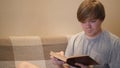 Young man reads book with interest. Concept. Student is intently reading old book sitting on sofa. Erudite young man Royalty Free Stock Photo