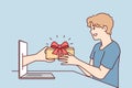 Young man receives present from hand poking out of laptop screen after online shopping. Vector image