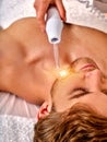 Young man receiving electric facial massage. Royalty Free Stock Photo