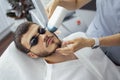 Young man receiving photo epilation while visiting beauty center on salon Royalty Free Stock Photo