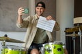 Young man records drum lesson on phone showing music sheet