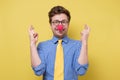 Young man with red clown nose and yellow tie making a wish