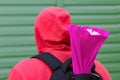 A young man in a red jacket with a hood on his head and a backpack on his back carries a gift in a bright package to his