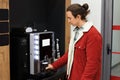 Young man in a red jacket is using an automatic coffee machine in an office or waiting area for a hot drink Royalty Free Stock Photo