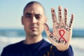 Young man with a red ribbon for the fight against AIDS in his ha