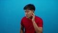 Young man in red shirt with confused expression against blue background Royalty Free Stock Photo