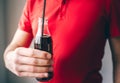 Young man in red shirt isolated over background. Guy hold glass bottle in hand with plastic straw inside. Coke delicious Royalty Free Stock Photo