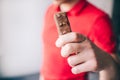 Young man in red shirt isolated over white background. Close up hand holding swet snack. Tasty delicious chocolate bar. Royalty Free Stock Photo
