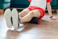 A young man in red shorts is doing exercises on a foam roller, works out of the muscles with a massage roller. Athletic