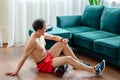 A young man in red shorts is doing exercises on a foam roller, works out of the muscles with a massage roller. Athletic