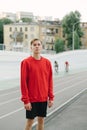Young man in a red sweatshirt stands on a sports track on a background of velodrome and bicycle.Portrait of a cyclist without a