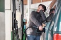 Young man refueling his vehicle while looking worried at the high gas prices.