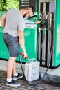 Young man refuling canister with fuel for his stalled automobile.