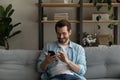 Young man relax on sofa use smartphone play game online Royalty Free Stock Photo