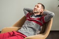 Man relaxes, lies in a chair, throwing his hands behind his head, closing his eyes and smiling Royalty Free Stock Photo