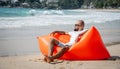 Young man relaxing on the beach while sitting on an inflatable sofa Royalty Free Stock Photo