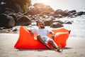 Young man relaxing on the beach while sitting on an inflatable sofa Royalty Free Stock Photo