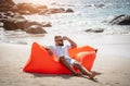 Young man relaxing on the beach while sitting on an inflatable sofa Royalty Free Stock Photo