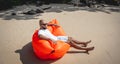 Young man relaxing on the beach while sitting on an inflatable sofa Royalty Free Stock Photo