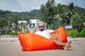 Young man relaxing on the beach while sitting on an inflatable sofa Royalty Free Stock Photo