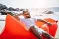 Young man relaxing on the beach while sitting on an inflatable sofa Royalty Free Stock Photo