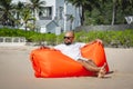 Young man relaxing on the beach while sitting on an inflatable sofa Royalty Free Stock Photo