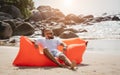 Young man relaxing on the beach while sitting on an inflatable sofa Royalty Free Stock Photo