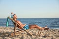 Young man relaxing in  chair on beach near sea Royalty Free Stock Photo