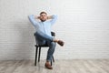 Young man relaxing on chair near white brick wall in office, space for text Royalty Free Stock Photo