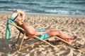 Young man relaxing in deck chair on beach near Royalty Free Stock Photo