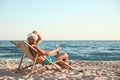 Young man relaxing in deck chair on beach Royalty Free Stock Photo