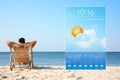 Young man relaxing in deck chair on beach and weather forecast widget. Mobile application Royalty Free Stock Photo