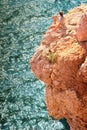 Young Man relaxing on rocky cliff with blue Sea on background Royalty Free Stock Photo