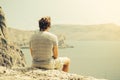 Young Man relaxing on rocky cliff Sea and mountains on background Royalty Free Stock Photo