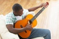 Young Man Relaxing Sitting On Sofa Playing Guitar