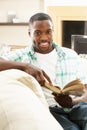 Young Man Relaxing Sitting On Sofa Reading Book Royalty Free Stock Photo