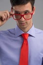 Young man removing glasses on grey background. Royalty Free Stock Photo