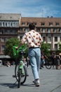 Young man with rental bike by velhop in the street wearing a printed floral shirt