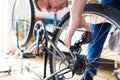 Young man repairing a bicycle at home. repairman installing assembling or adjusting bicycle gear on wheel in workshop. Royalty Free Stock Photo