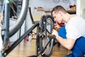 Young man repairing a bicycle at home. repairman installing assembling or adjusting bicycle gear on wheel in workshop. Royalty Free Stock Photo