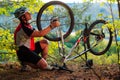 Young man repairing mountain bike in the forest Royalty Free Stock Photo