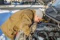 A young man repairs a car engine on the road Royalty Free Stock Photo