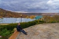 A young man is resting on a bench in cloudy cold autumn weather. The concept of solitude with nature Royalty Free Stock Photo