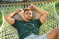 Young man resting in comfortable hammock at garden Royalty Free Stock Photo