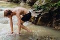 Young man resting by mountain river while traveling in nature